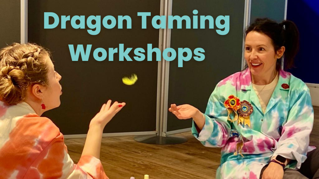 A marketing image for Dragon Taming Workshops, two women in tied dyed lab coats keep a feather mid air by blowing on it