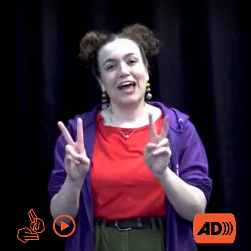 Steph, a curly haired woman, wearing a red top and purple hoody signs. In the corners are the icons for BSL, video and Audio Description